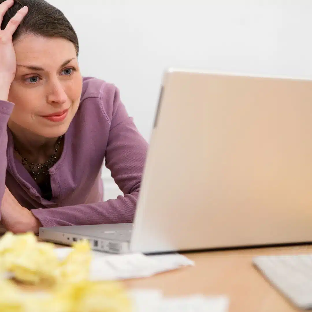 Frau sitzt frustriert und mit leicht traurigem Blick vor Laptop